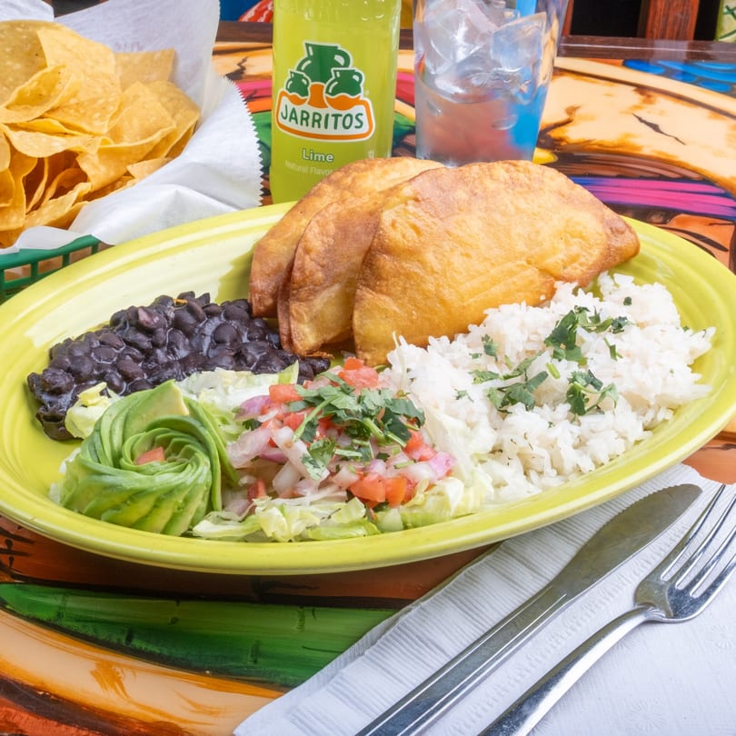 A Fiesta Cancún Mexican Restaurant meal with fried empanadas, rice, black beans, avocado, and salsa.